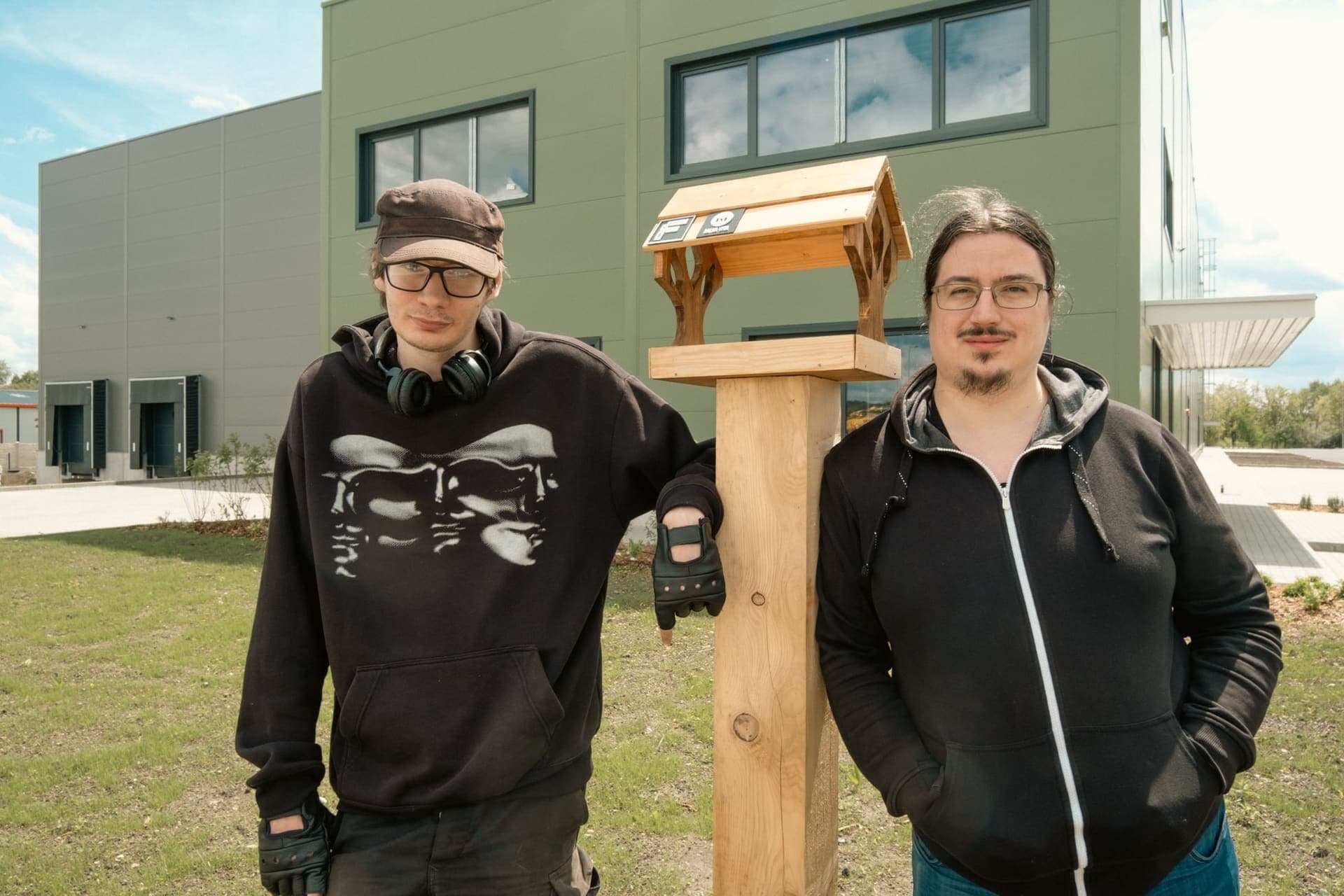 Two makers from the Salva Vita Foundation standing beside the handcrafted bird feeder they built for Faedra Group